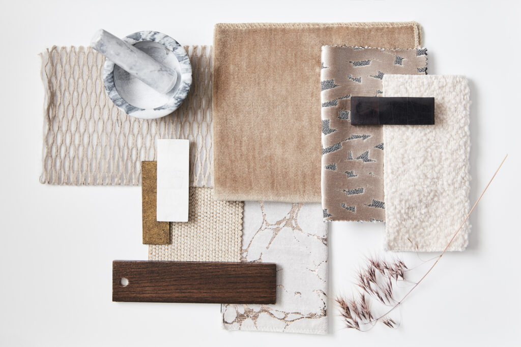 Flat lay of interior design mood board materials, including marble mortar and pestle, wood and cork samples, and neutral fabric and rug swatches